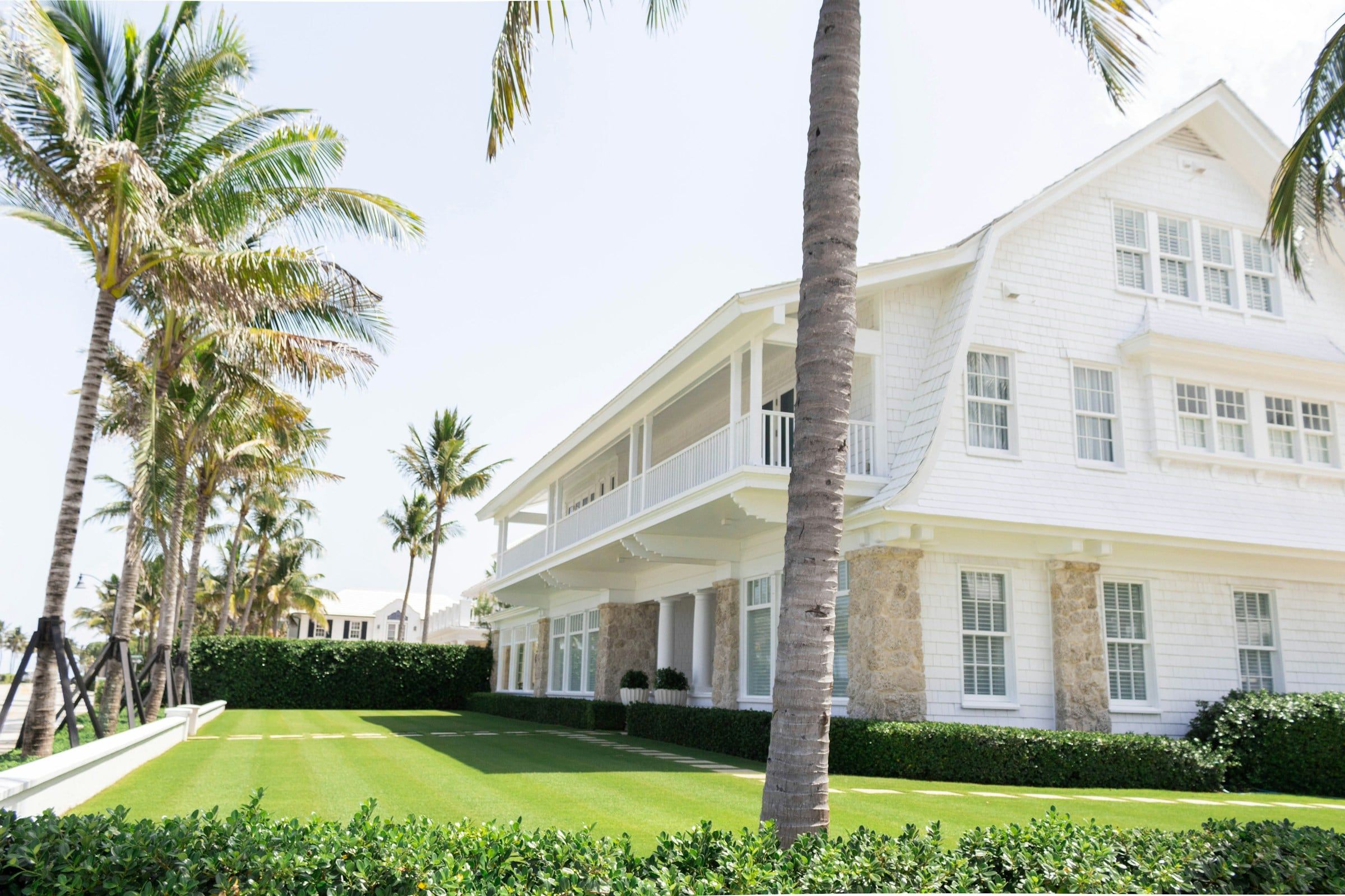 Large white home with palm trees and a manicured lawn